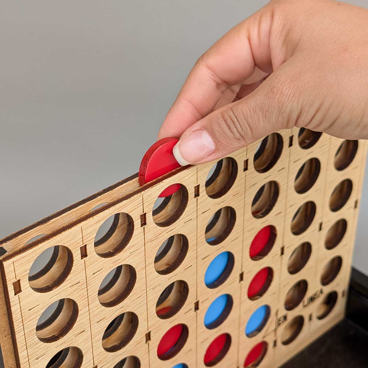 Juego 4 en línea de madera, perfecto para jugar en familia y estimular el pensamiento lógico. Foto referencia de cómo se insertan las ficha en el tablero