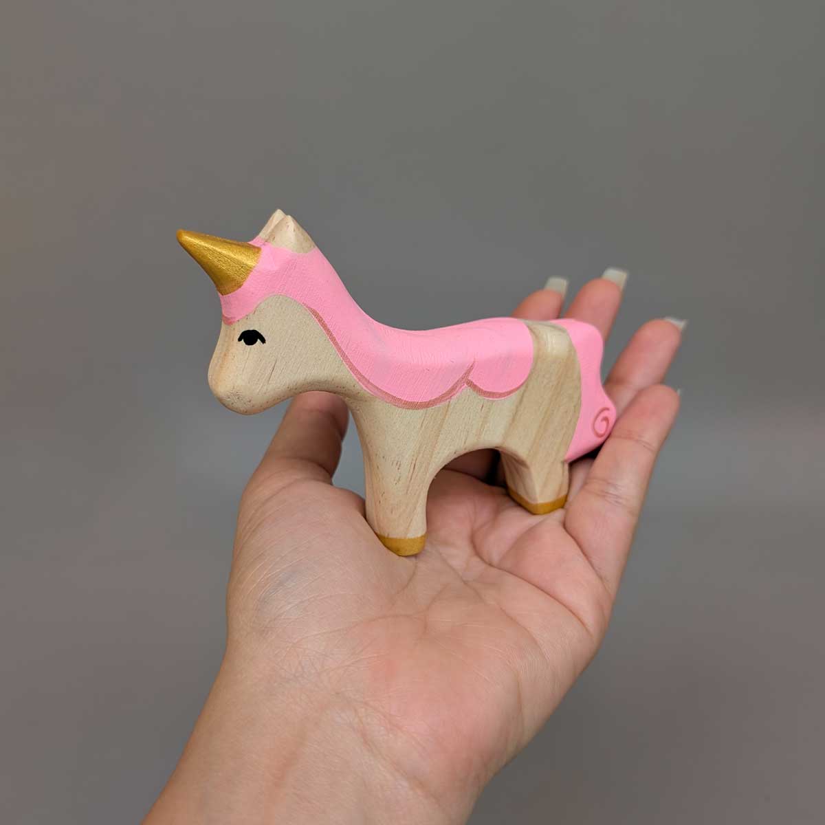 Unicornio de madera, juguete Montessori artesanal para estimular la imaginación infantil. Referencia de tamaño en mano