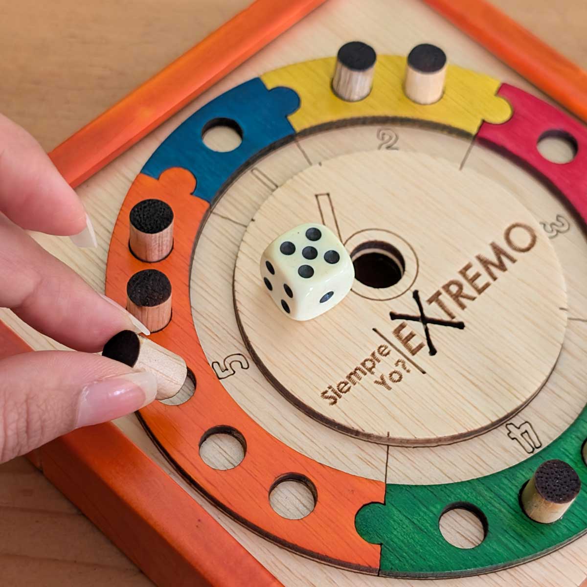 Juego de mesa ¿Por qué siempre yo? versión pequeña en madera, ideal para compartir en familia y divertirse en cualquier lugar. Imagen detalle caja, fichas y dado