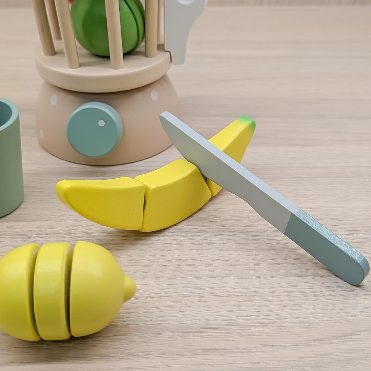 Licuadora de madera artesanal para niños, estimula la imaginación y el juego simbólico. Imagen detalle banano, limón y cuchillo de madera