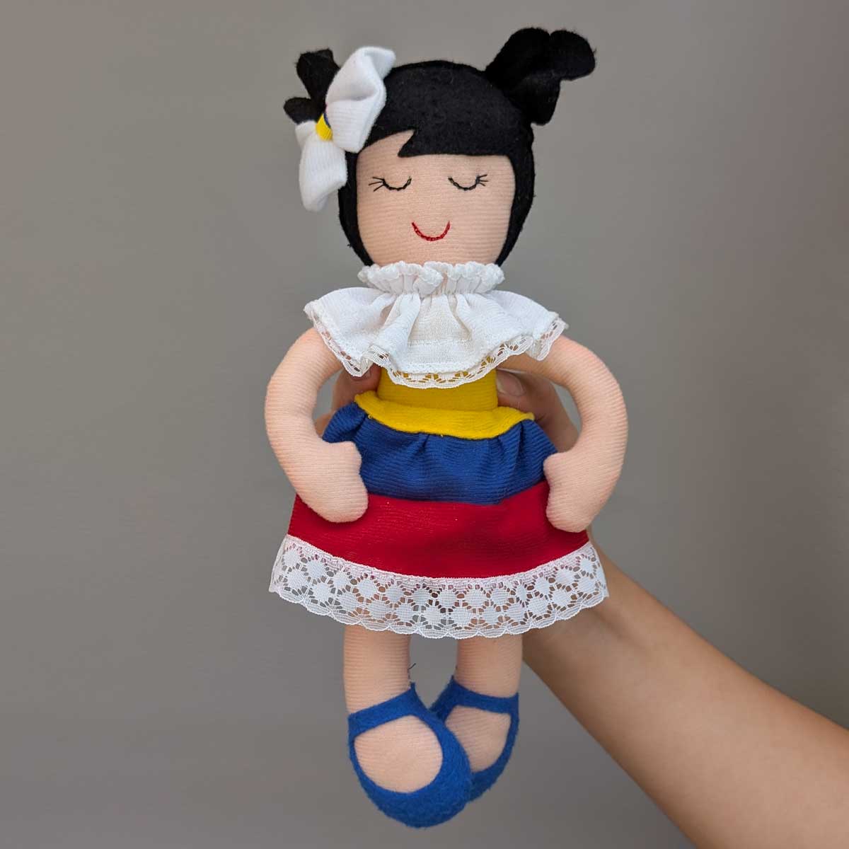 Colombianita de tela, muñeca hecha a mano con vestuario típico y detalles representativos del país. Referencia de tamaño con mano