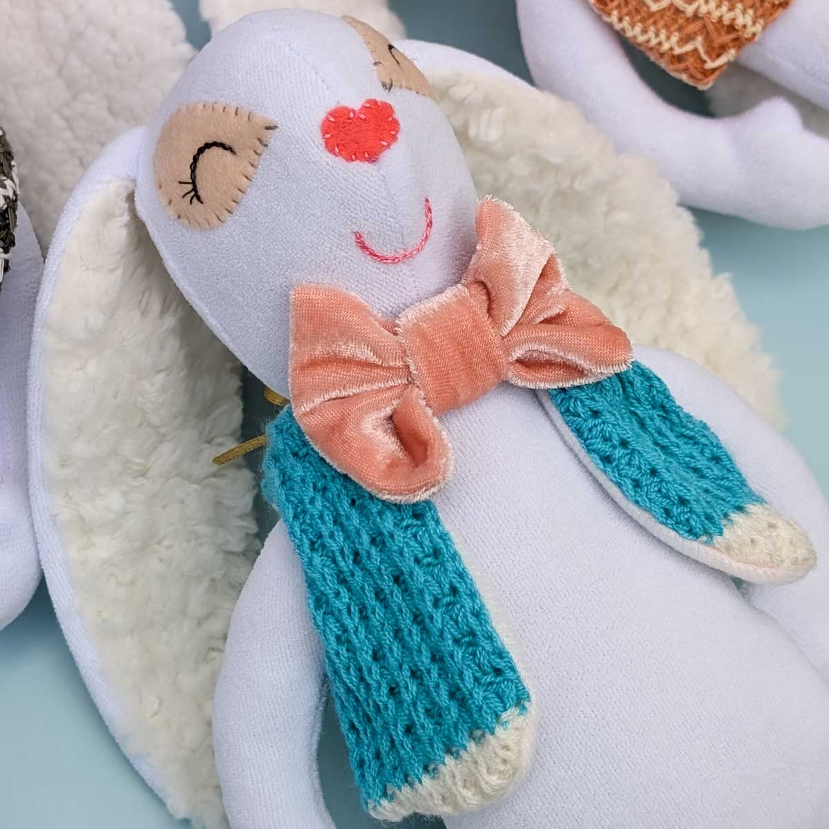 Peluche de conejo en tela, suave, hecho a mano en Colombia. Regalo niños. Foto detalle carita, orejas, moño y chaleco azul claro
