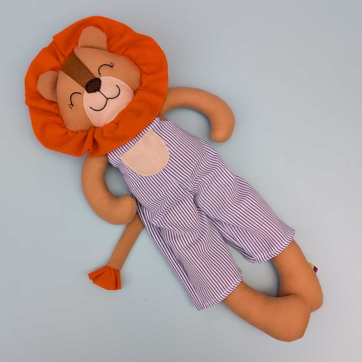 Peluche león hecho a mano en Colombia, ideal para estimular el afecto y el juego en niños. Imagen del peluche de león cuerpo completo. Vestido a rayas blanco y azul