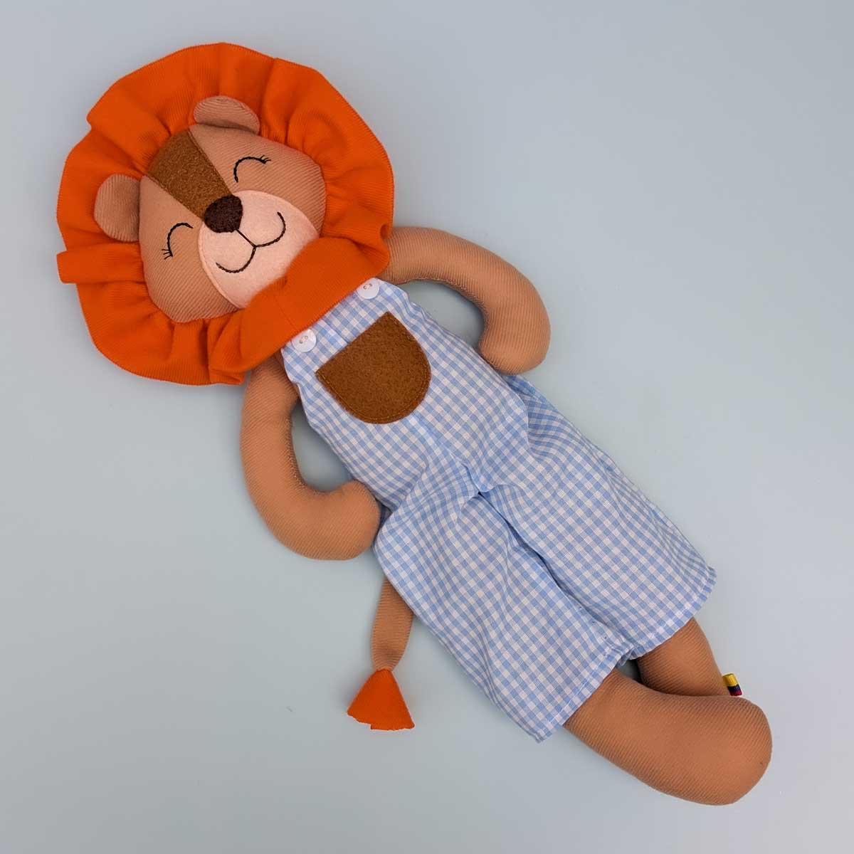 Peluche león hecho a mano en Colombia, ideal para estimular el afecto y el juego en niños. Imagen del peluche de león cuerpo completo. Vestido a cuadro blanco y azul