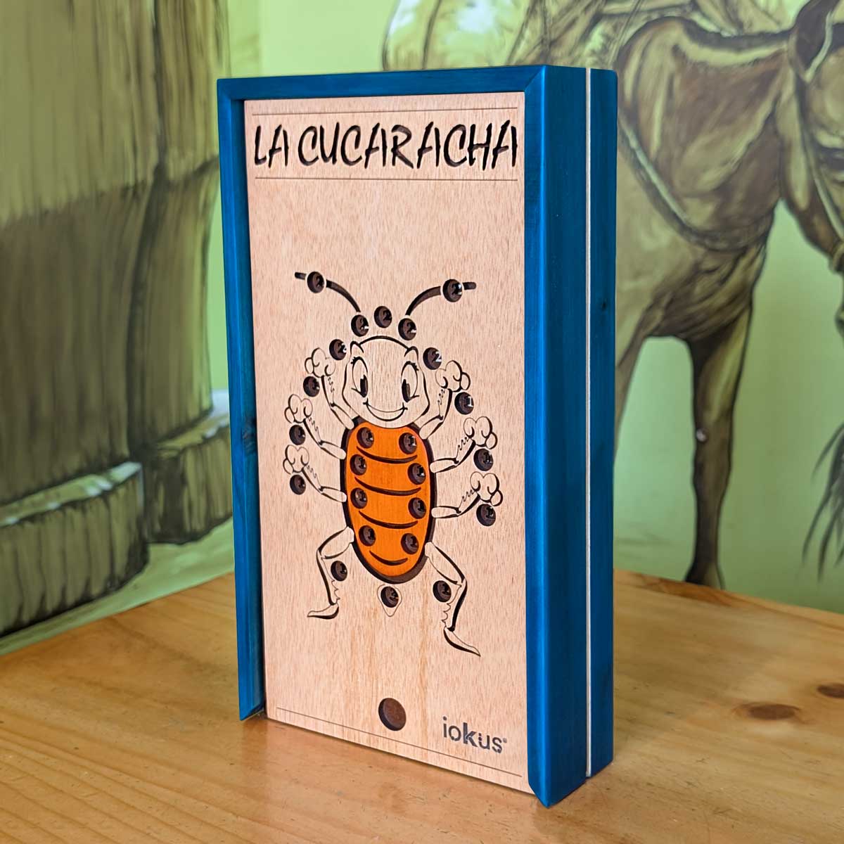Juego La Cucaracha en madera, ideal para integración y diversión en familia. Imagen de la caja color azul