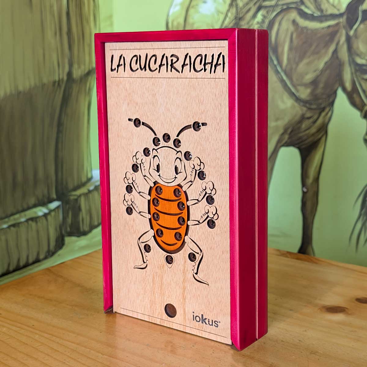 Juego La Cucaracha en madera, ideal para integración y diversión en familia. Imagen de la caja color roja