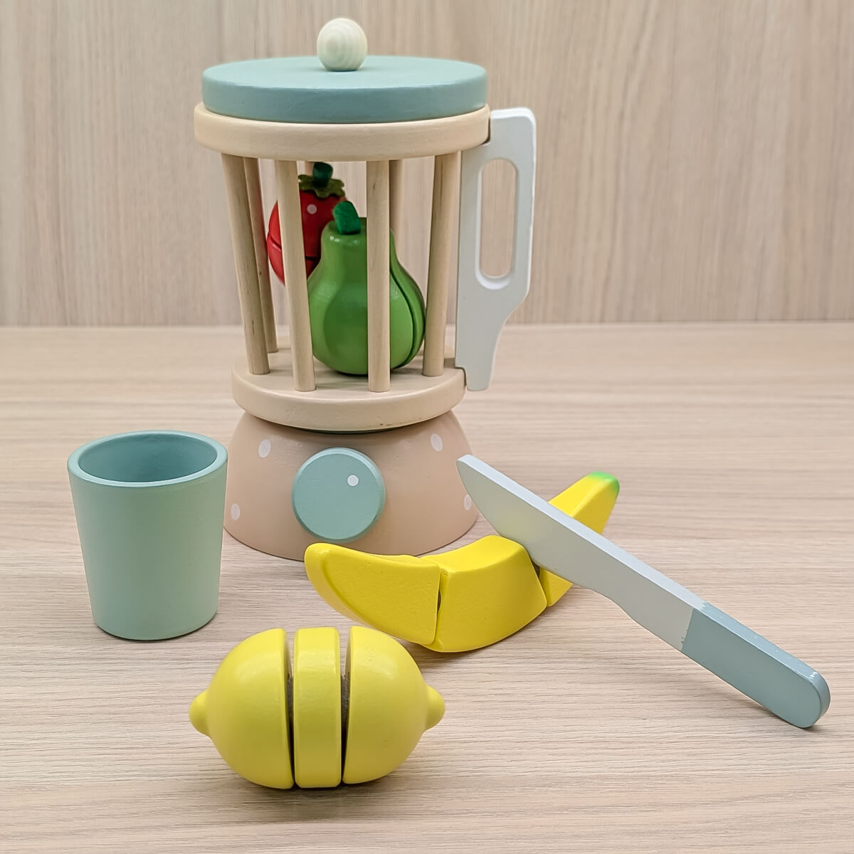 Licuadora de madera artesanal para niños, estimula la imaginación y el juego simbólico. Imagen de los elementos que incluye (licuadora, vaso, cuchillo, limón, banano, fresa y pera todo en madera)